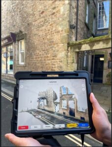 a hand holding an ipad up, looking at a building, using laser scanning equipment to create an up-to-date detailed 3D digital map of local streets and public spaces